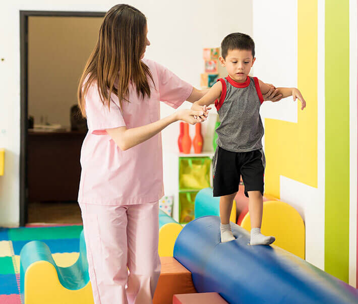 Physical therapy: a therapist helping a boy balance on a foam roller