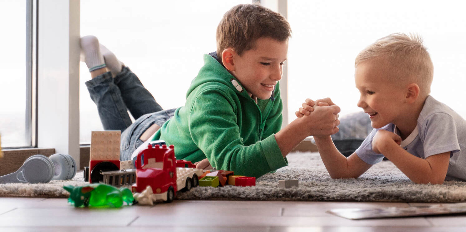 Two boys arm wrestling on the floor