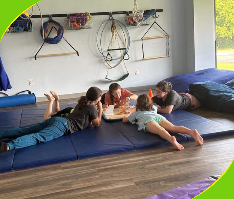 Children and a therapist lying on mats in a therapy gym