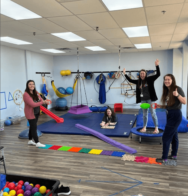 Therapists in a therapy gym with mats and swings
