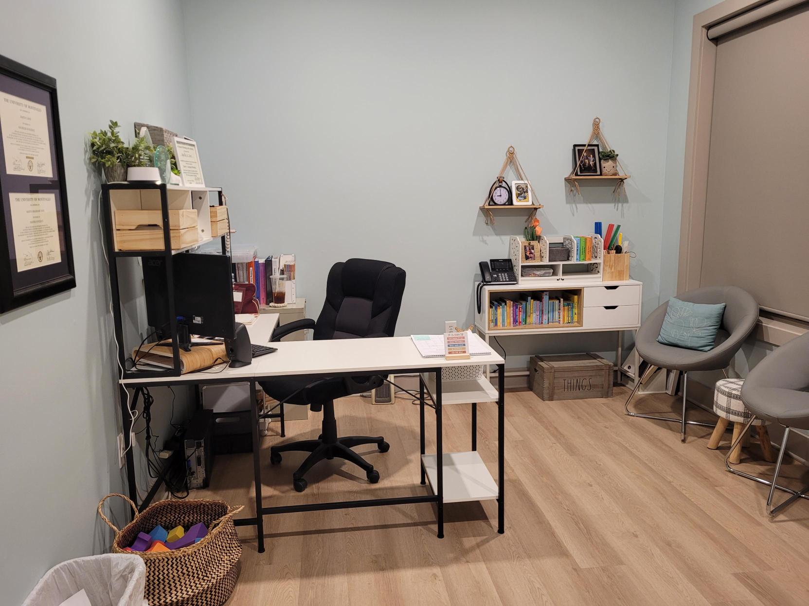 Therapy room with a desk, chairs and toy shelves