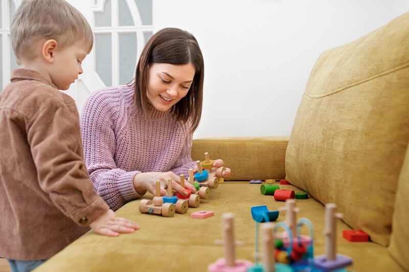 Toddler and adult playing with wooden toys