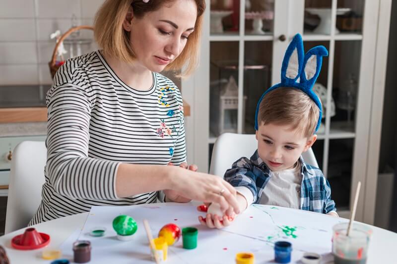 Boy painting with an adult