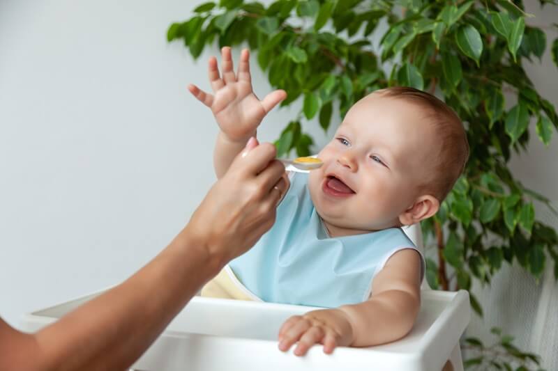Baby being spoon-fed in a high chair