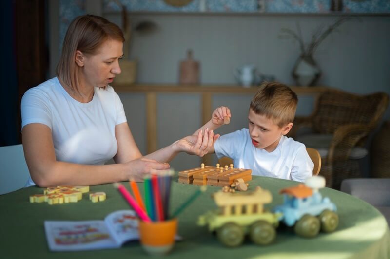 Therapist and boy playing with toys at a table
