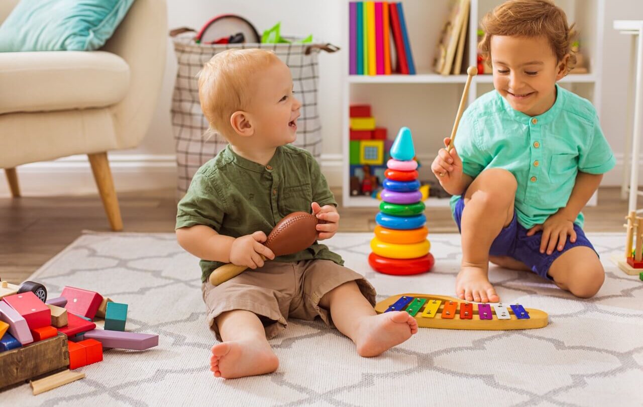 Two toddlers playing with toys on a rug