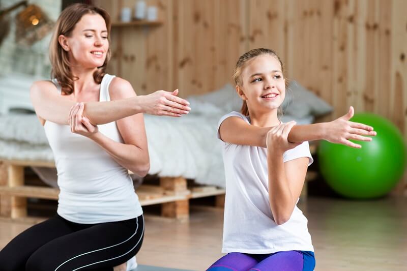 Therapist and girl stretching together