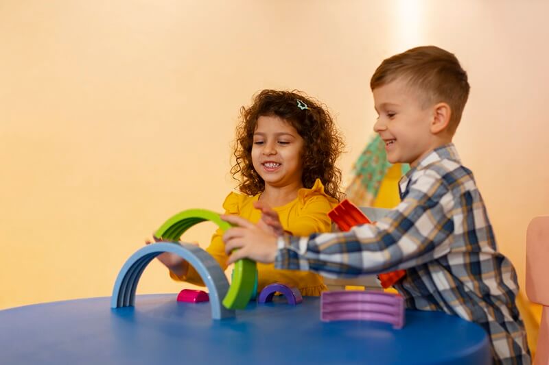 Two children playing with a rainbow toy