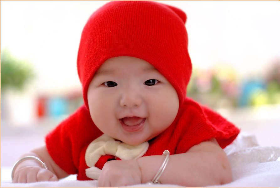 Baby lying on its tummy in a red hat
